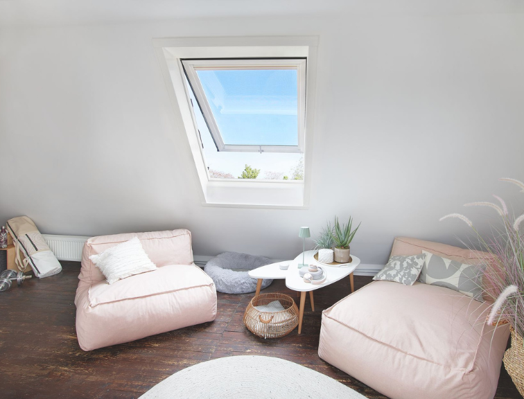 Gemütliche Sitzecke mit moderner Einrichtung und einem Roto Designo R8 Dachfenster, das natürlichen Tageslichteinfall ermöglicht