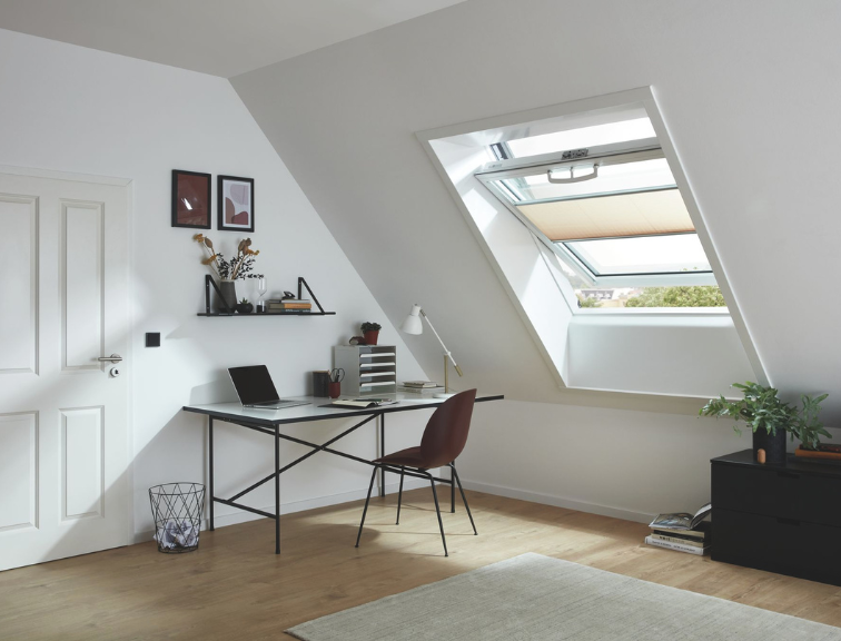 Arbeitsplatz mit modernem Schreibtisch unter einem Roto Dachfenster, das viel natürliches Tageslicht in den Raum bringt