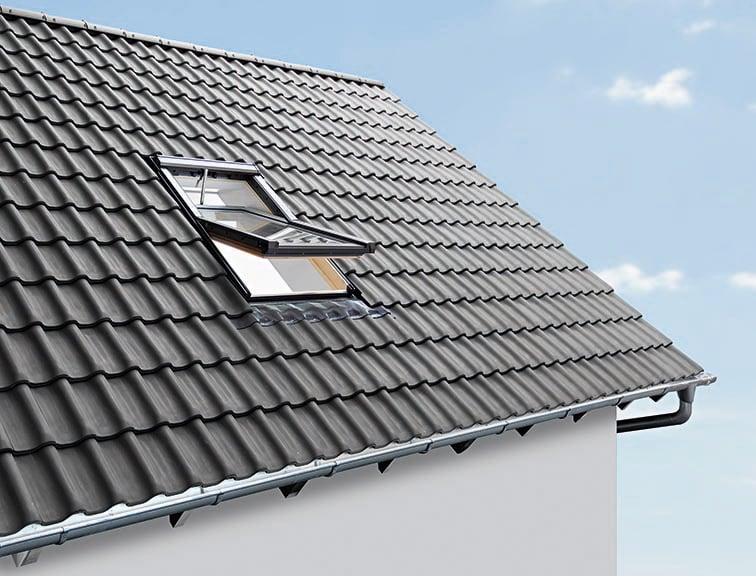 Geöffnetes Roto QT4 Dachfenster in grauer Ausführung, fotografiert von außen auf dem Dach