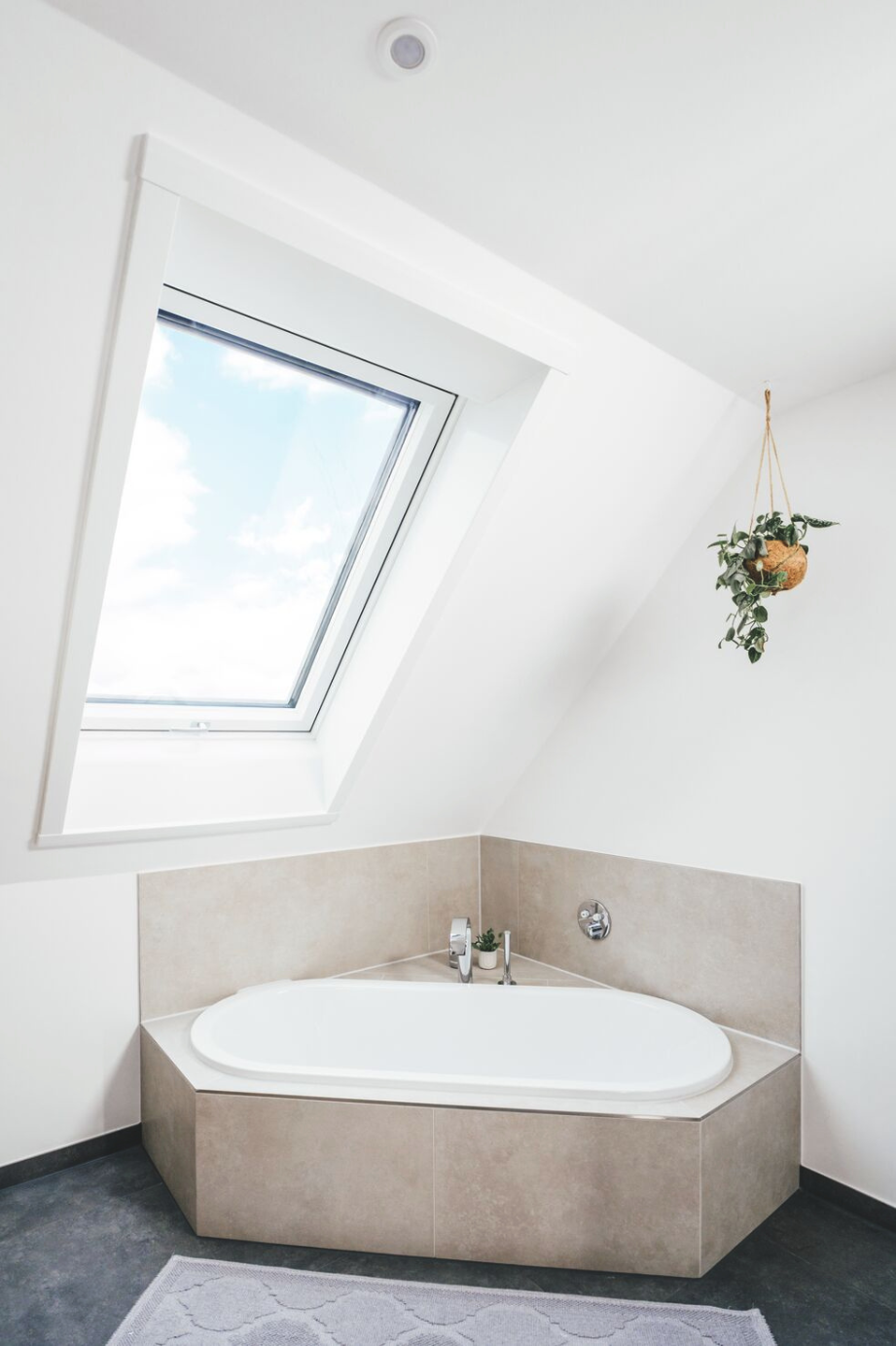 Badezimmer mit Eckbadewanne und Roto Designo R8 Dachfenster für optimalen Tageslichteinfall und modernes Wohngefühl
