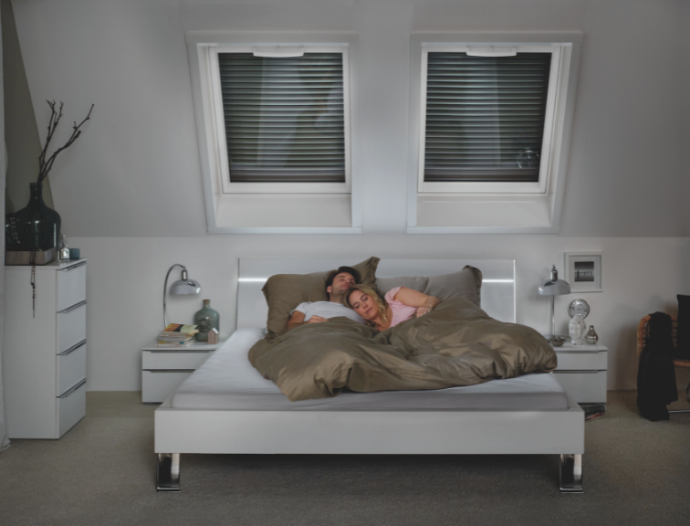 Schlafendes Ehepaar in abgedunkeltem Schlafzimmer mit Roto Außenrollladen