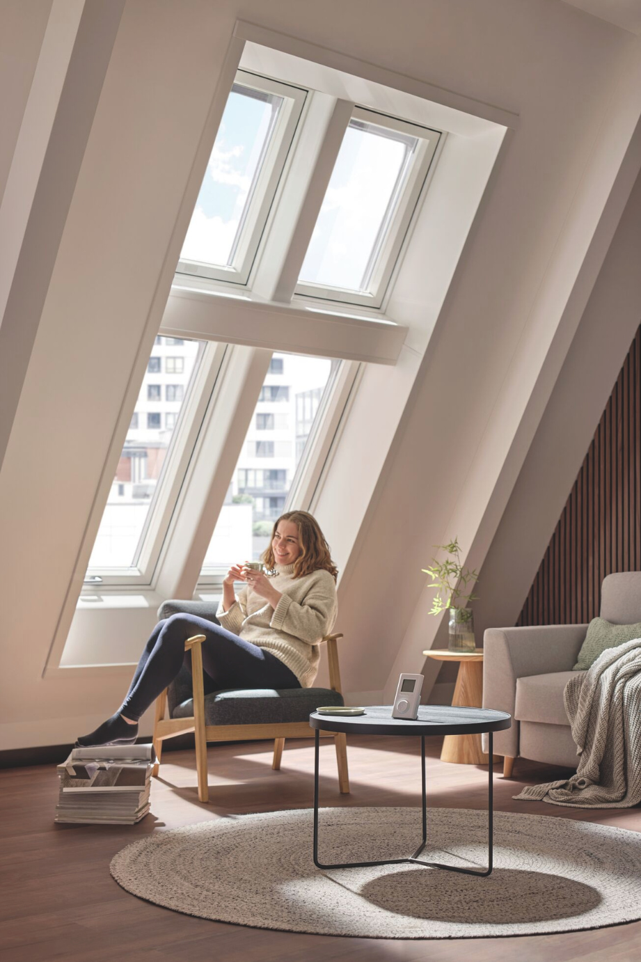 Innenraum mit Frau unter einem Roto Designo Heat Dachfenster für angenehme Licht- und Wärmewirkung