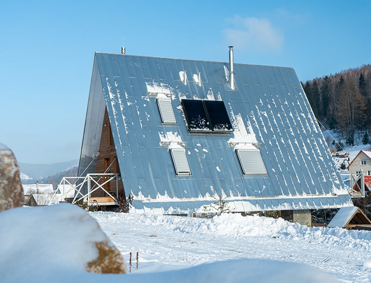 Blick auf ein Haus im Schnee mit leicht verschneitem Dach und geschlossenen Roto Außenrollläden
