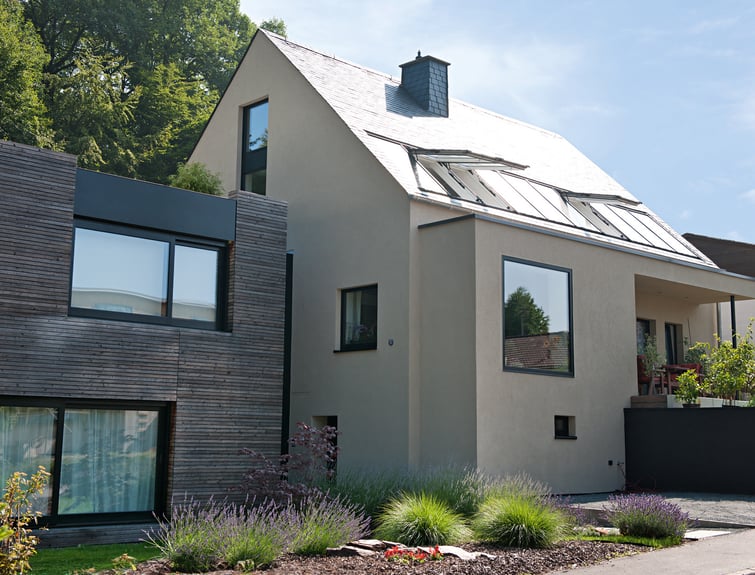 Modernes Haus mit Holzanbau und Vorgarten und geöffneten Roto Dachfenstern