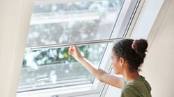 roto-frau-zieht-insektenschutzrollo-am-dachfenster-nach-unten