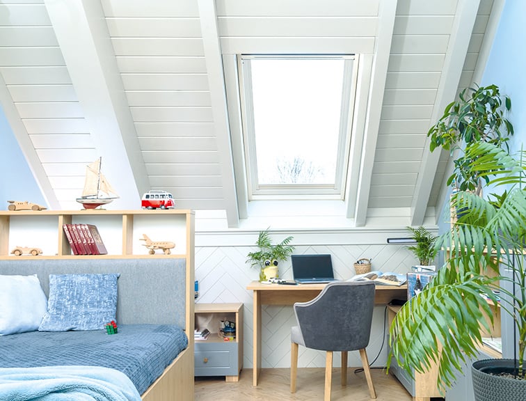 Jugendzimmer unter dem Dach mit Schreibtisch und Bett.