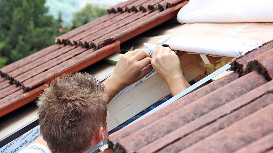 handwerker-prueft-daemmung-am-dachfenster