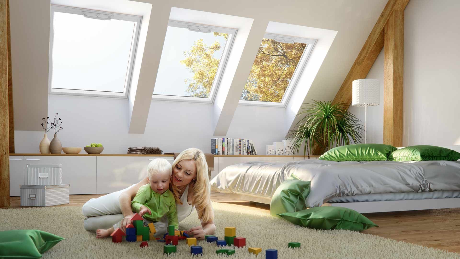 Frau mit Baby spielt unter dem Dachfenster