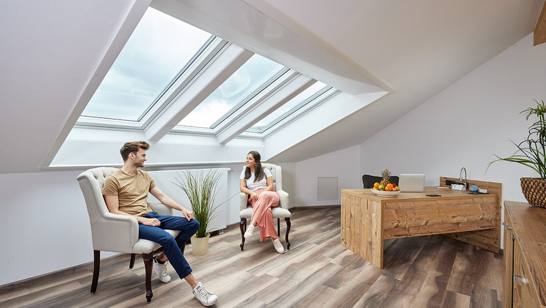 Blick fällt in einen Dachwohnraum mit drei nebeneinander eingebauten Dachfenstern